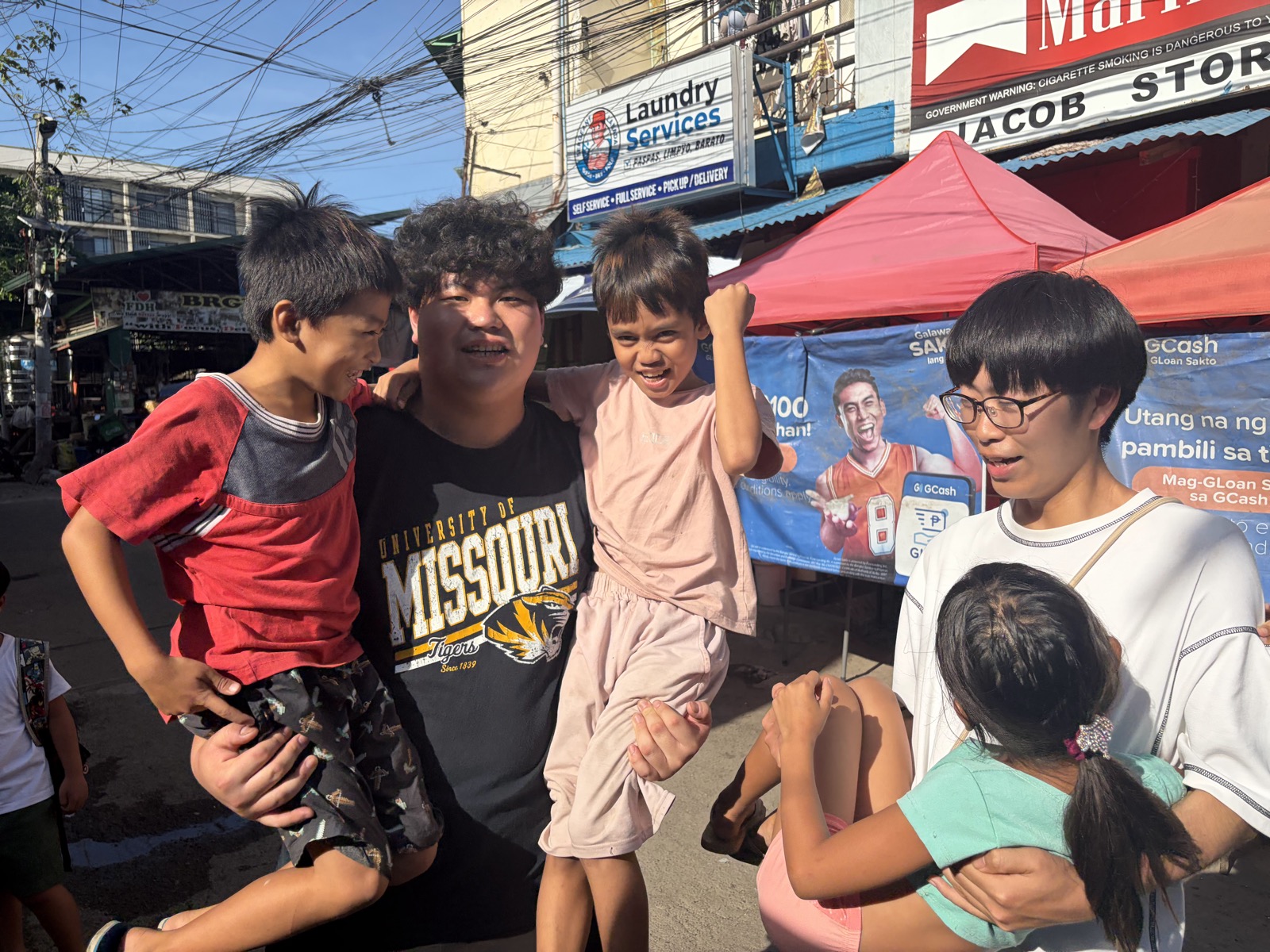 商店が並ぶ通りで現地の子どもたちと肩を寄せ合う参加者